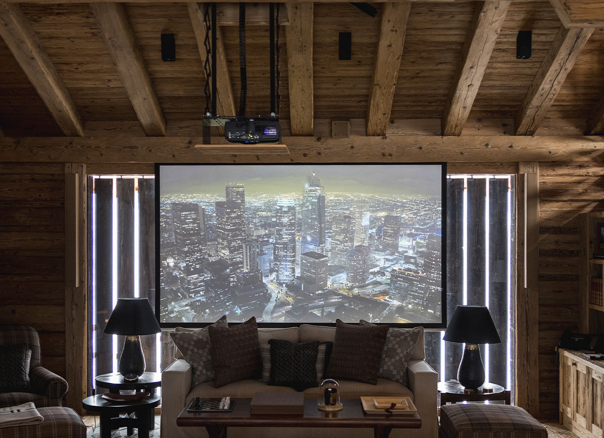 Rustikales Heimkino mit Projektorbildschirm, gemütlicher Sofaecke und L-Acoustics Lautsprechern.